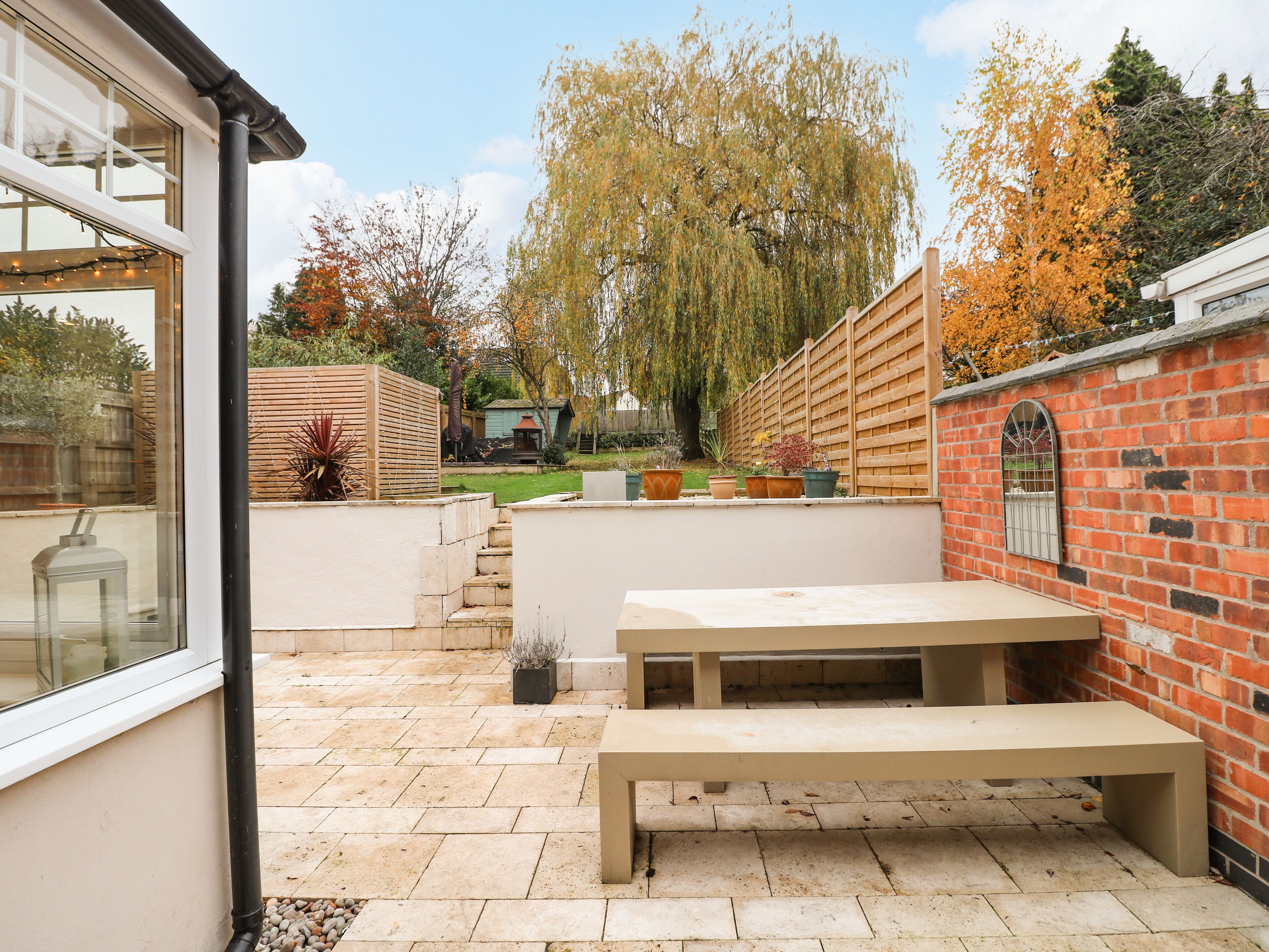 A patio with a bench, a brick wall, and a wooden fence.