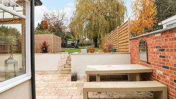 A patio with a bench, a brick wall, and a wooden fence.