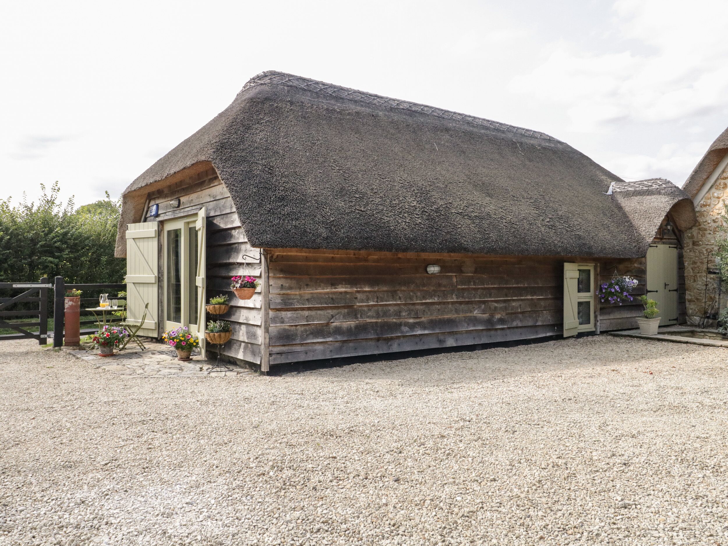 A rustic thatched-roof building with a gravel driveway.
