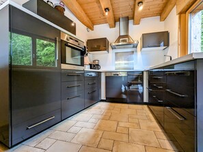 A modern kitchen with built-in appliances, a large window, and a herringbone floor pattern.