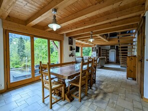 A wooden interior with a dining table, chairs, and a view of the outdoors.