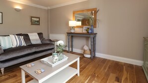 A living room with a dark brown sofa, a white coffee table, a wooden fireplace, and a mirror above it. - 4 Fishermans Wharf (Whitstable)