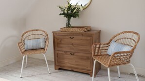 Two wicker chairs with cushions, a wooden dresser, and a mirror on the wall. - 4 Fishermans Wharf (Whitstable)