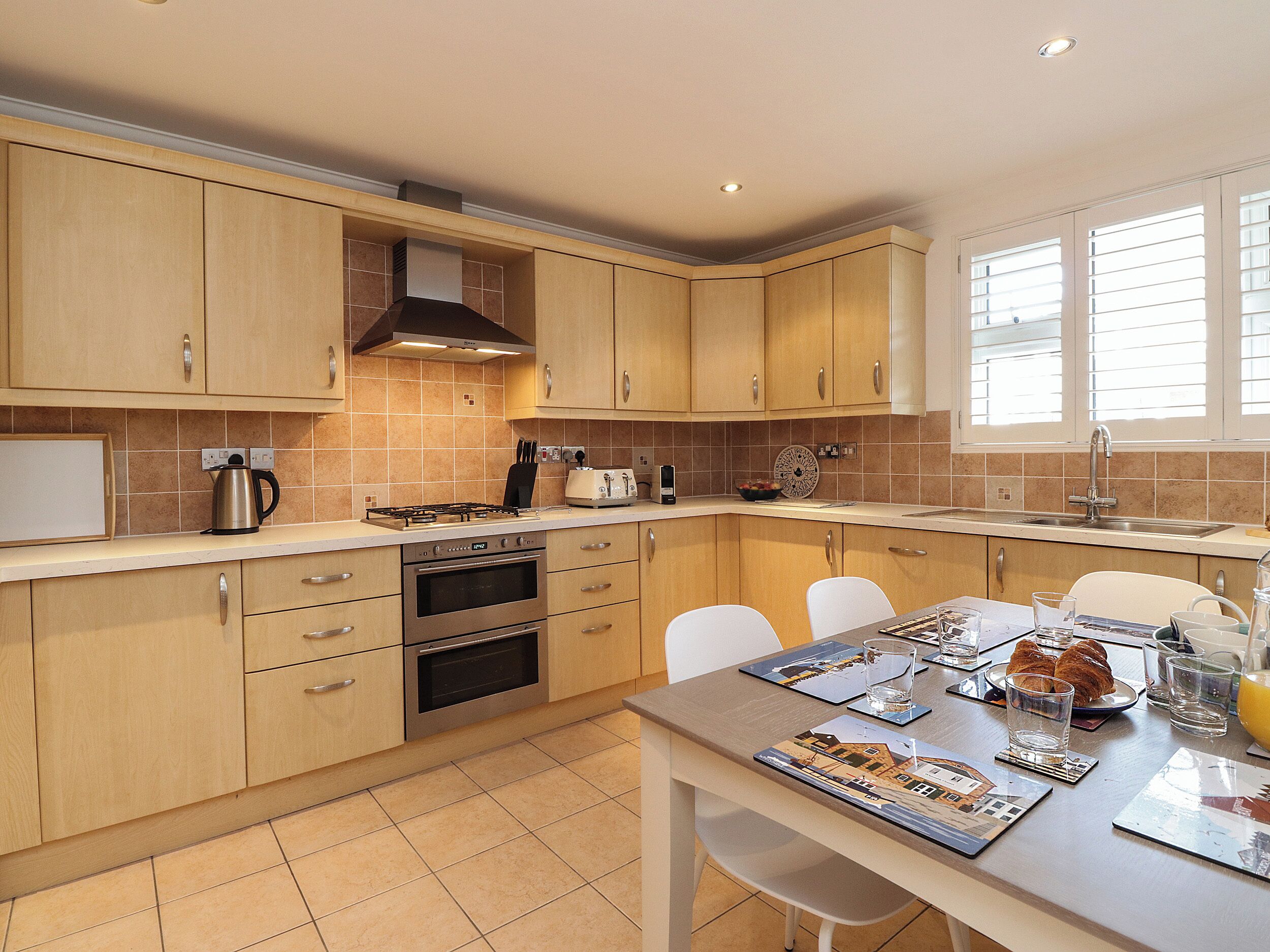 A modern kitchen with wooden cabinets, a gas stove, and a dining area with a table set for two.