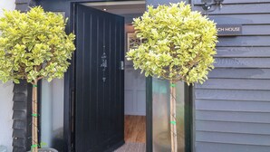 A black door with a sign reading "Beach House" above it, flanked by two potted plants. - The Coach House, Bank Top Farm (Ashbourne)