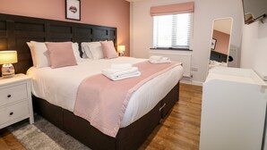 A neatly arranged bedroom with a large bed, bedside tables, a window with blinds, and a mirror. - The Coach House, Bank Top Farm (Ashbourne)