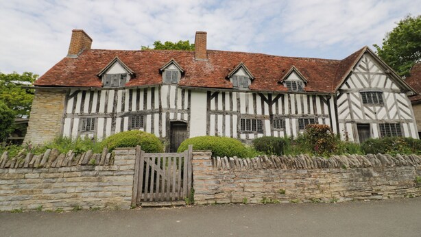 A traditional Tudor-style building with a stone wall and a wooden gate. - The Garden House (Stratford-upon-Avon)