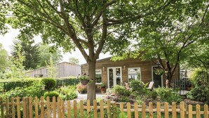 A wooden house with a garden in front, a wooden fence, and a gravel path. - The Garden House (Stratford-upon-Avon)