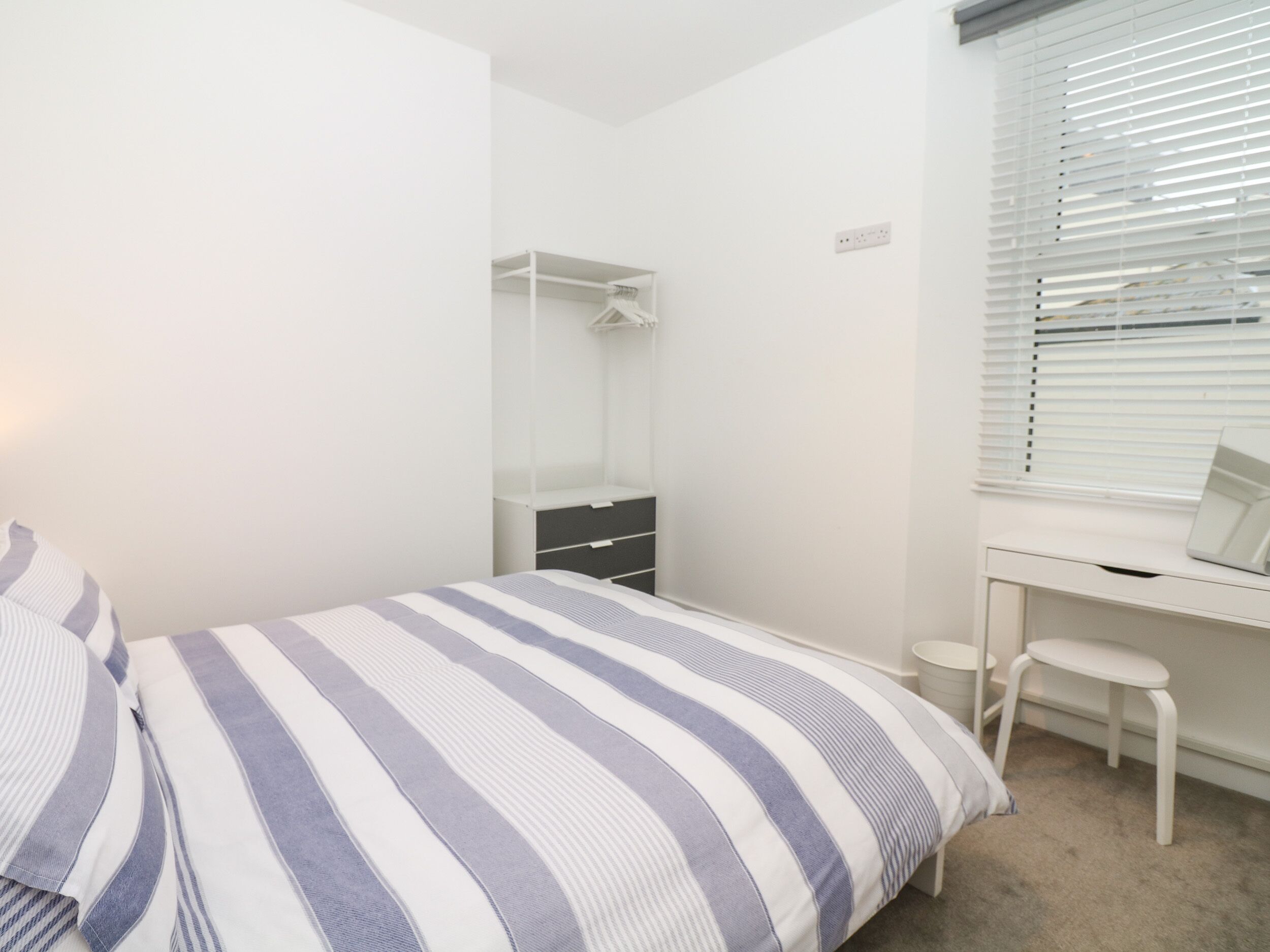A bedroom with a bed, a desk, a chair, and a wardrobe.