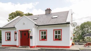 A white house with red trim and a red door. - Lough Mask Road Fishing Cottage (Neale)