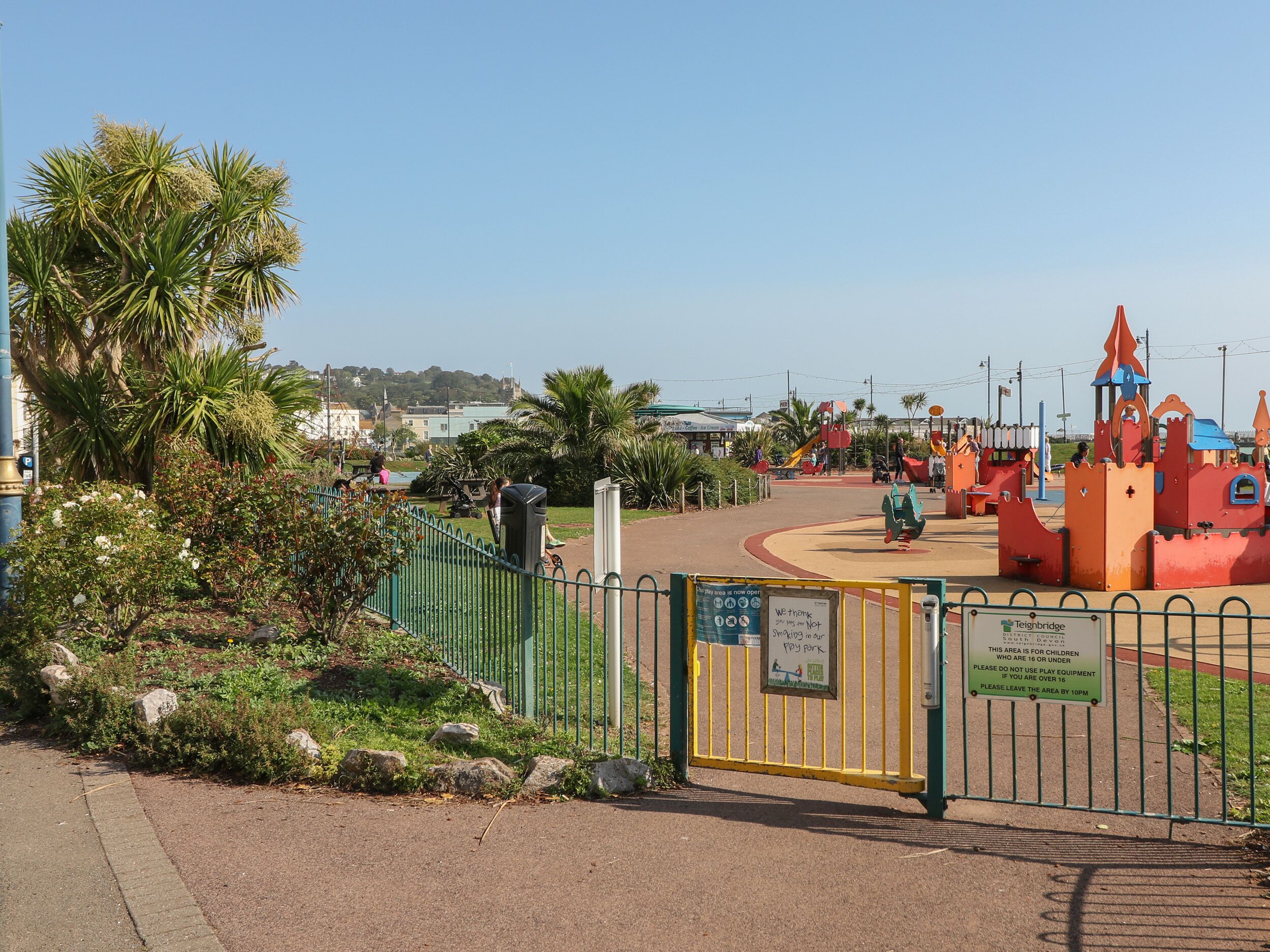 A fenced playground area with a castle-like play structure and a sign indicating it is for children under 16.