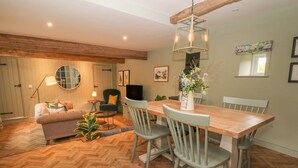 Un coin repas avec une table et des chaises en bois, un miroir rond, un canapé et une lampe.