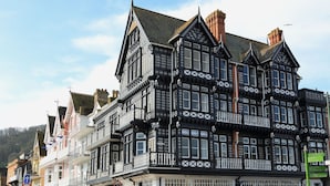 Een historiek zwart-wit gebouw met meerdere verdiepingen, met traditionele architectuurdetails en een opvallend balkon.
