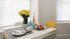 A dining table with a vase of flowers, a bottle, and a plate of food. - Samphire (Teignmouth)