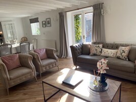 Una sala de estar con sofá, dos sillones, una mesa de centro y un comedor con mesa y sillas.