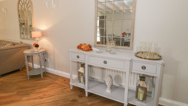 A white console table with a mirror, a lamp, and decorative items. - The Granary (Bedford)