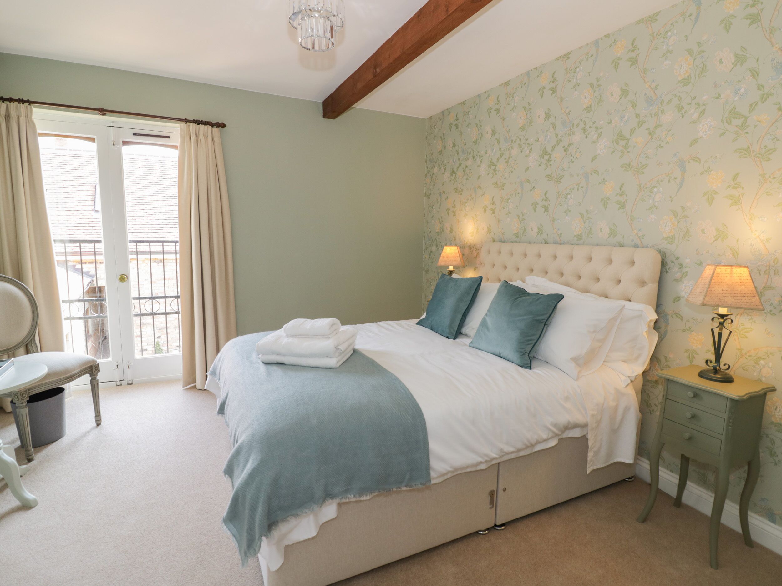 A bedroom with a bed, two bedside lamps, a chair, and a window with curtains.