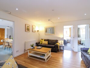 A living room with a sofa, coffee table, and a dining area with chairs. - BB House (Bedford)
