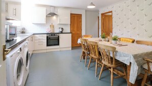 Eine kompakte Küche mit Mikrowelle, Backofen und Waschmaschine. Ein Essbereich mit Tisch und Stühlen vorhanden.