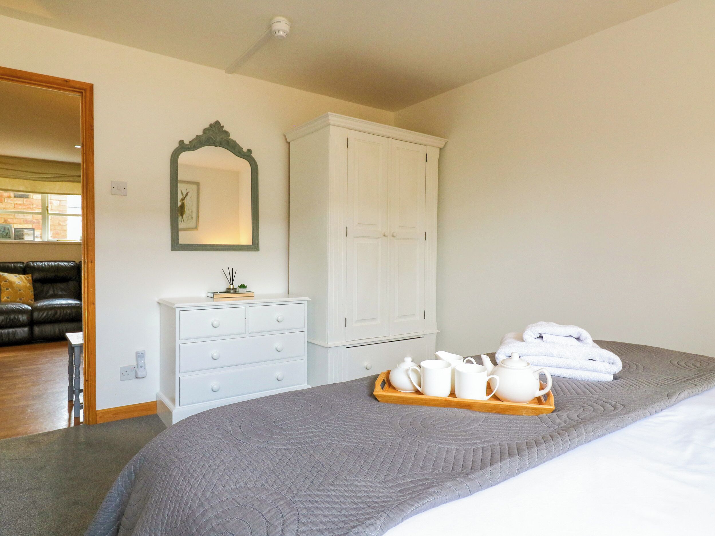 Quarto com cama, penteadeira, guarda-roupa, espelho e bandeja com chá.