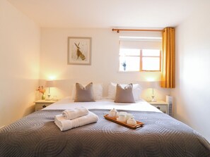 A hotel room with a bed, two bedside tables, a window with curtains, a wall-mounted artwork, and a tray with tea sets. - BB House (Bedford)