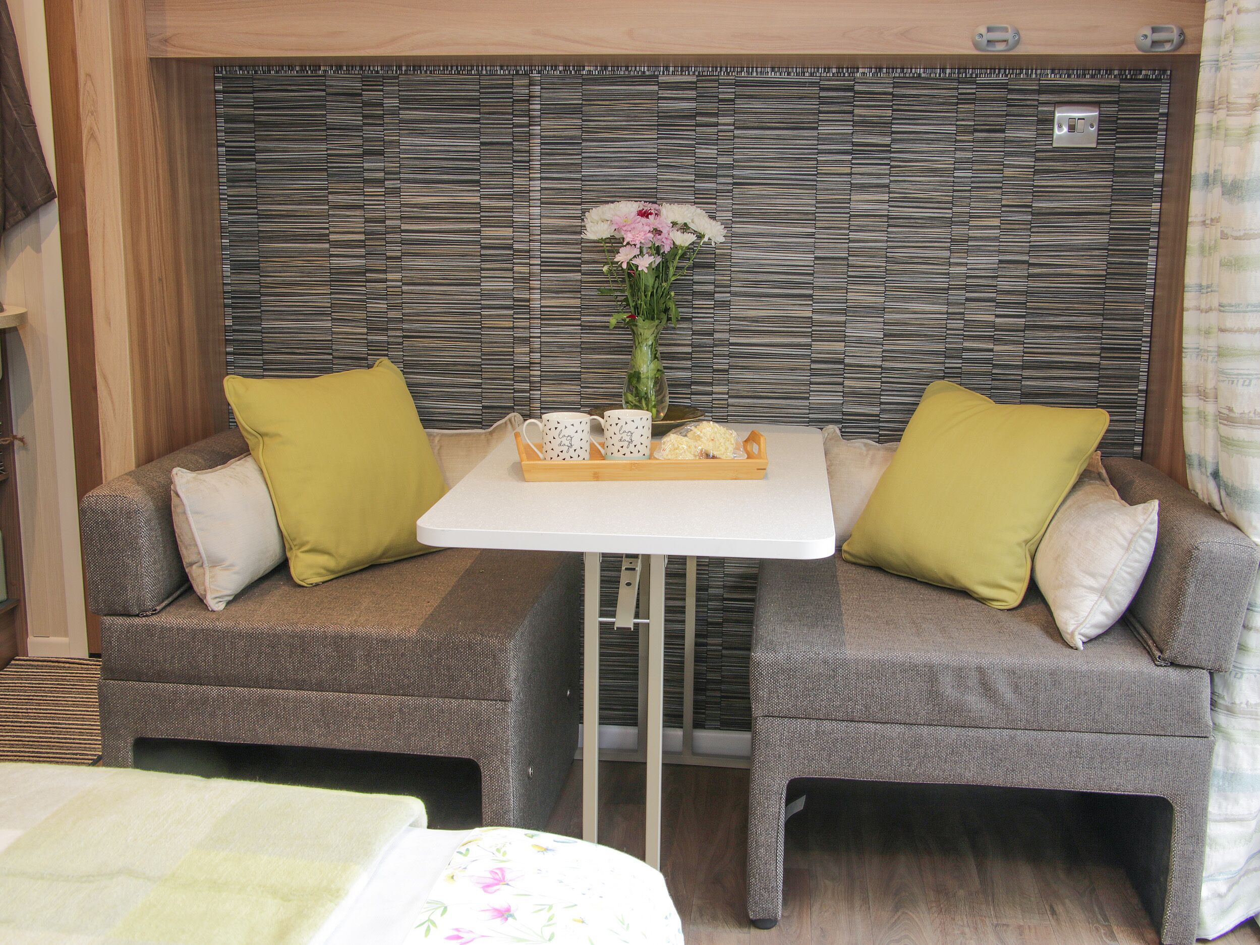 A cozy seating area with two sofas, a small table, and a decorative vase with flowers.
