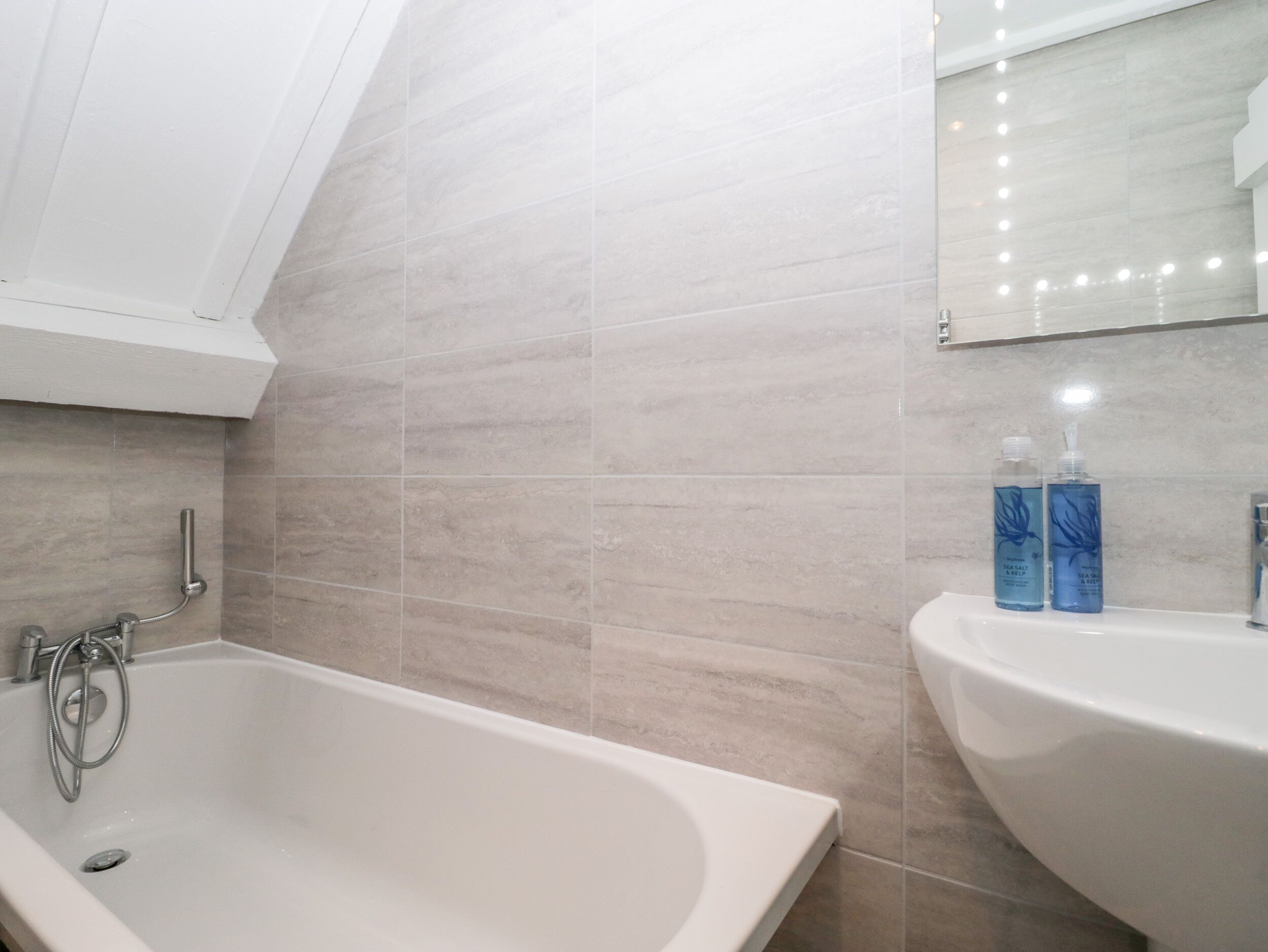 A modern bathroom with a freestanding bathtub, a sink, and a mirror above the sink.