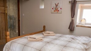 A neatly made bed with a plaid bedspread and two folded towels. - Wren (Scarborough)
