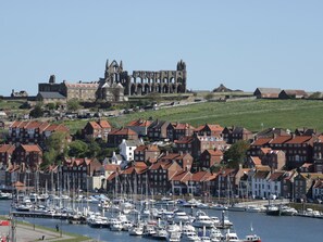 A coastal town with historic buildings, a marina with numerous boats, and a prominent cathedral in the background.