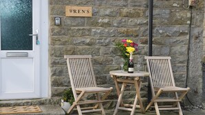 Two wooden chairs and a table outside a stone building with a 'WREN'S' sign. - Wren (Scarborough)
