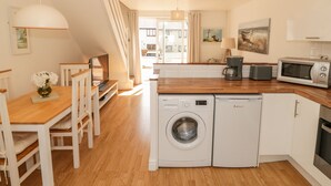 A compact kitchen with a washing machine, microwave, and coffee maker. - Ketch Cottage (Holyhead)