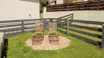 Un patio con dos sillas de madera y un camino de piedra.