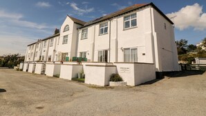 A two-story white building with a flat roof and multiple windows. - Ketch Cottage (Holyhead)