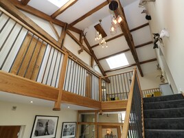 A spacious interior with a wooden staircase, a skylight, and a chandelier.