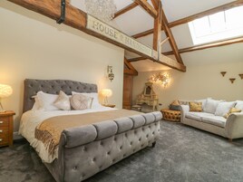 A bedroom with a large bed, a sofa, a dresser, and a chandelier.