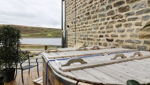 A stone wall with a wooden deck and a hot tub. - Snave Barn (Skipton)