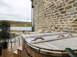 A stone wall with a wooden deck and a hot tub.
