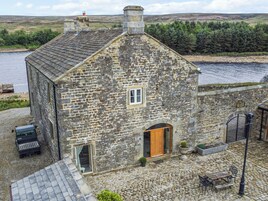 Una casa de piedra con puerta de madera, una ventana pequeña y un patio empedrado.