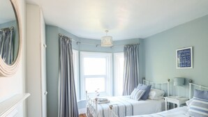 A bedroom with two beds, a mirror, a bedside table, a lamp, and a framed quote on the wall. - Elm Villa (Wareham)