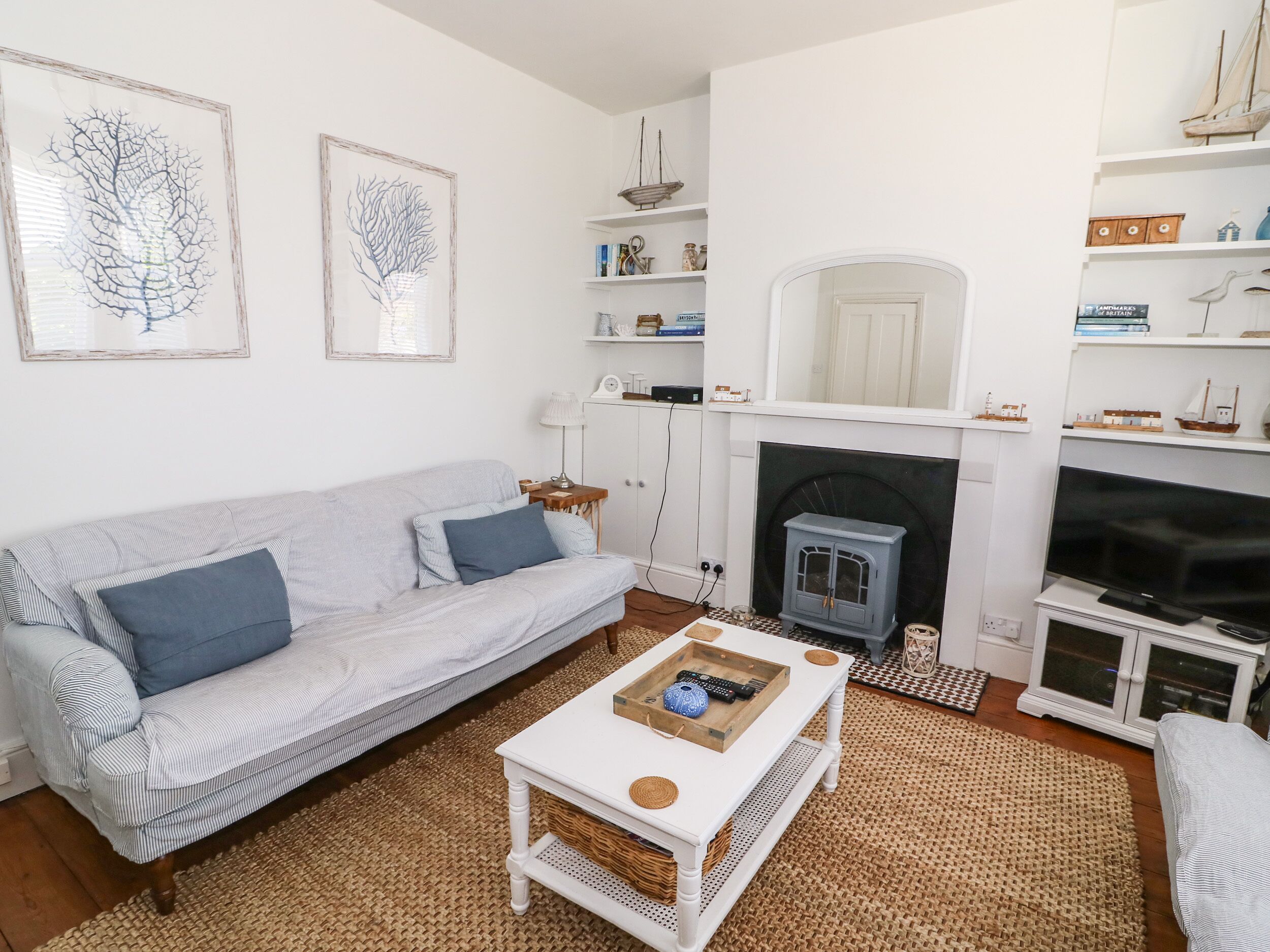 A living room with a white sofa, a coffee table, a fireplace, and nautical decor.