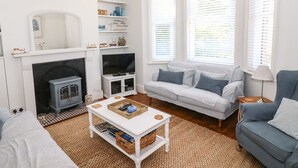 A living room with a fireplace, a sofa, a television, and a coffee table. - Elm Villa (Wareham)