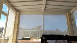 A covered patio with a table and chairs, large windows, and a view of a building and landscape. - Trullo new villa with private heated pool near Salento beaches (Ugento)