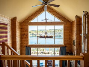 A wooden cabin with a large window offering a view of a lake and forest. - Casa Loma (Carnforth)