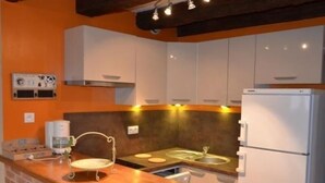 Een keuken met witte kastjes, een bakstenen muur en een houten aanrecht.