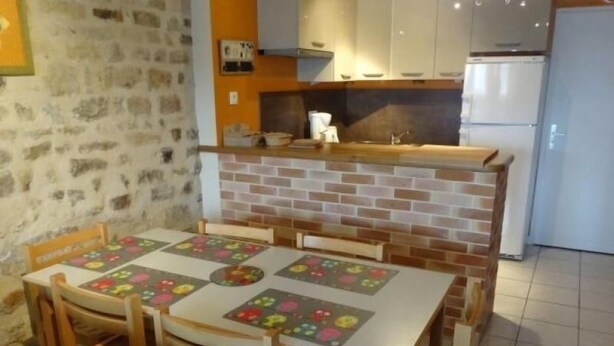 Een eetgedeelte met een tegelwand, houten stoelen en een tafel met een kleurrijke placemat.