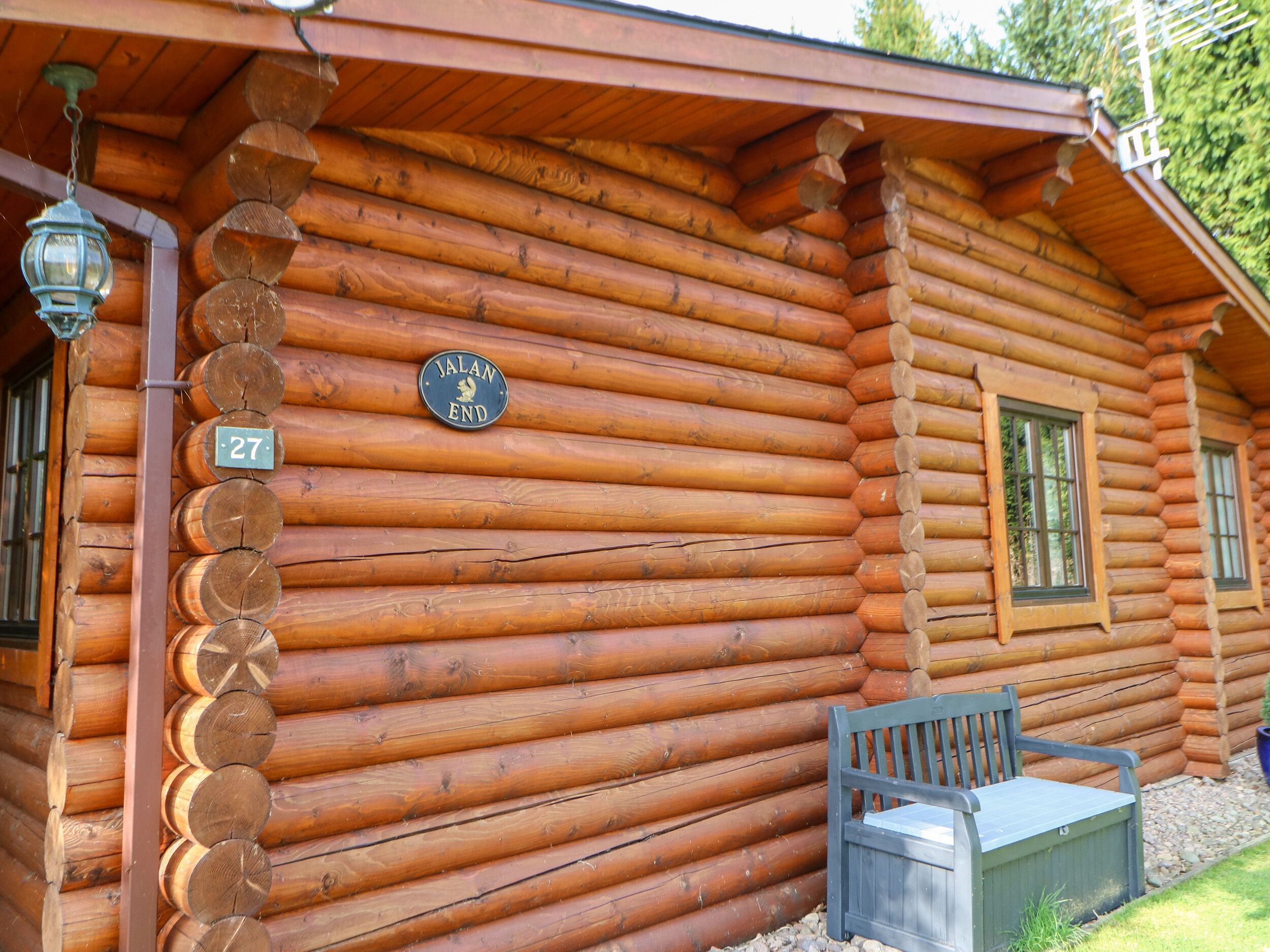 A log cabin with a wooden exterior, a bench outside, and a sign reading "JALAN END".
