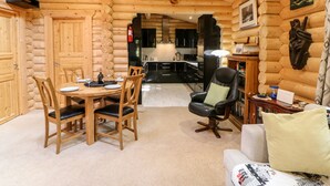 A log cabin interior with a dining area, kitchen, and seating space. - Jalan End (Morpeth)