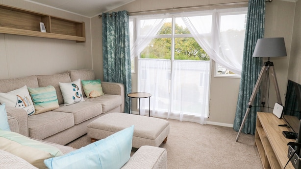 A cozy living room with a beige sofa, a small round table, and a lamp. - Ystwyth 26 (Borth)