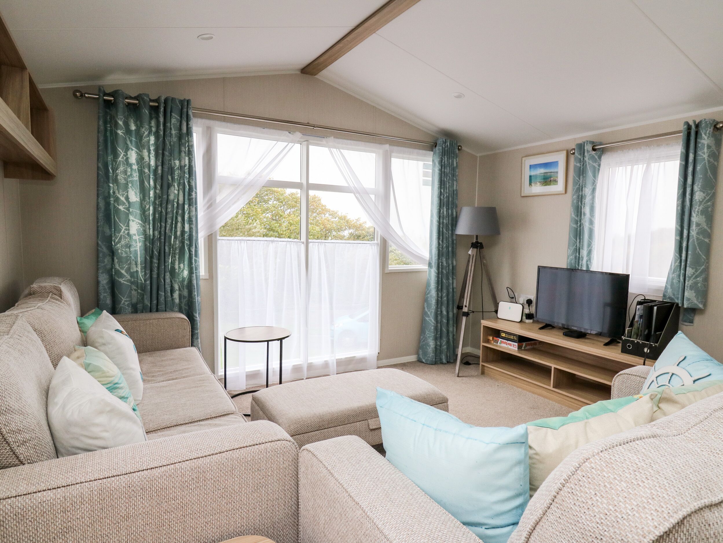 A cozy living room with a sofa set, a small round table, and a television on a wooden stand.
