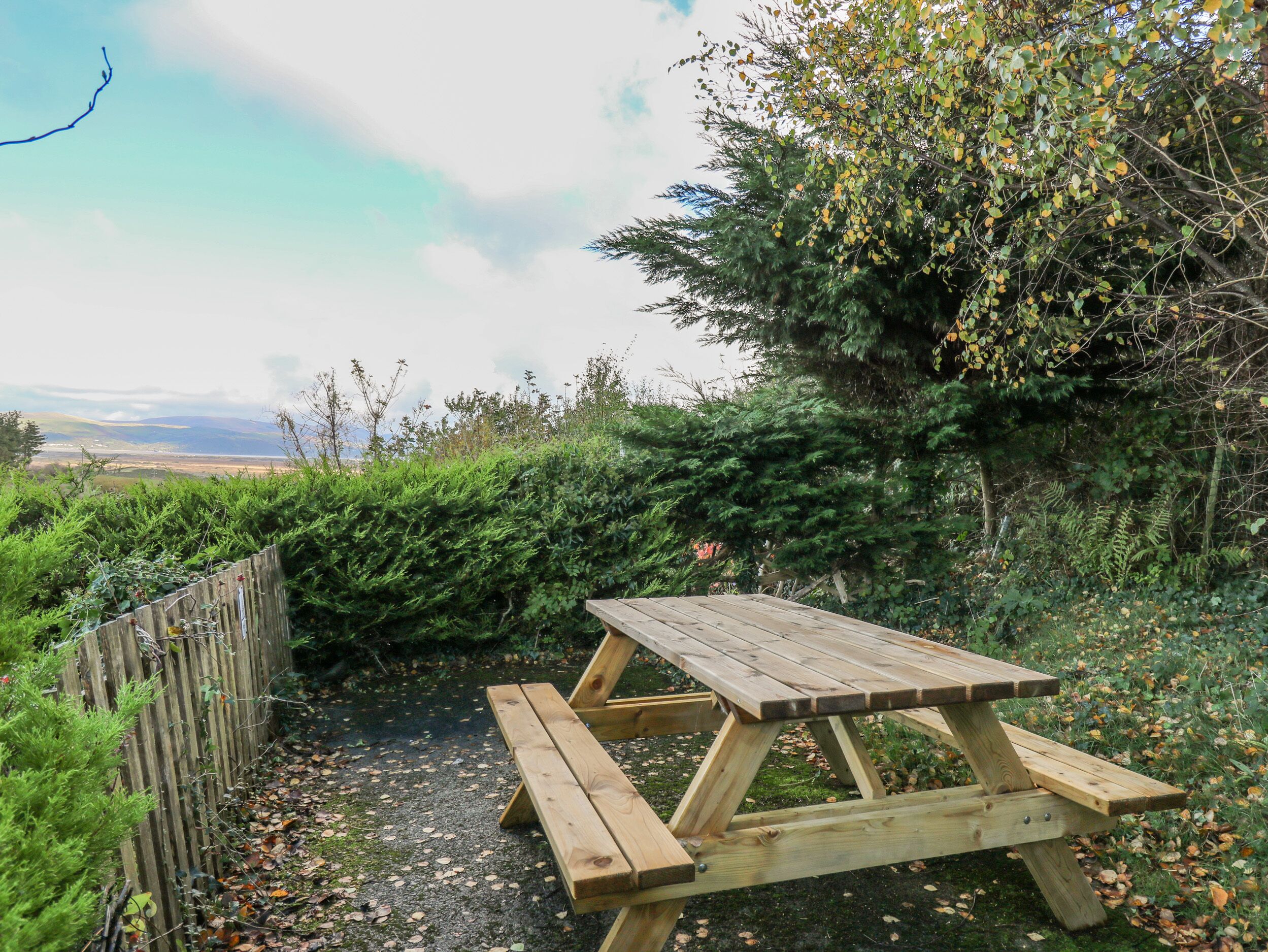 Una mesa de picnic de madera en un entorno natural, con vistas a colinas distantes.